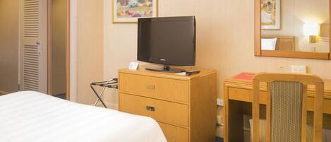 Une chambre d’hôtel avec un lit, un bureau en bois, une télévision, une chaise et un miroir.