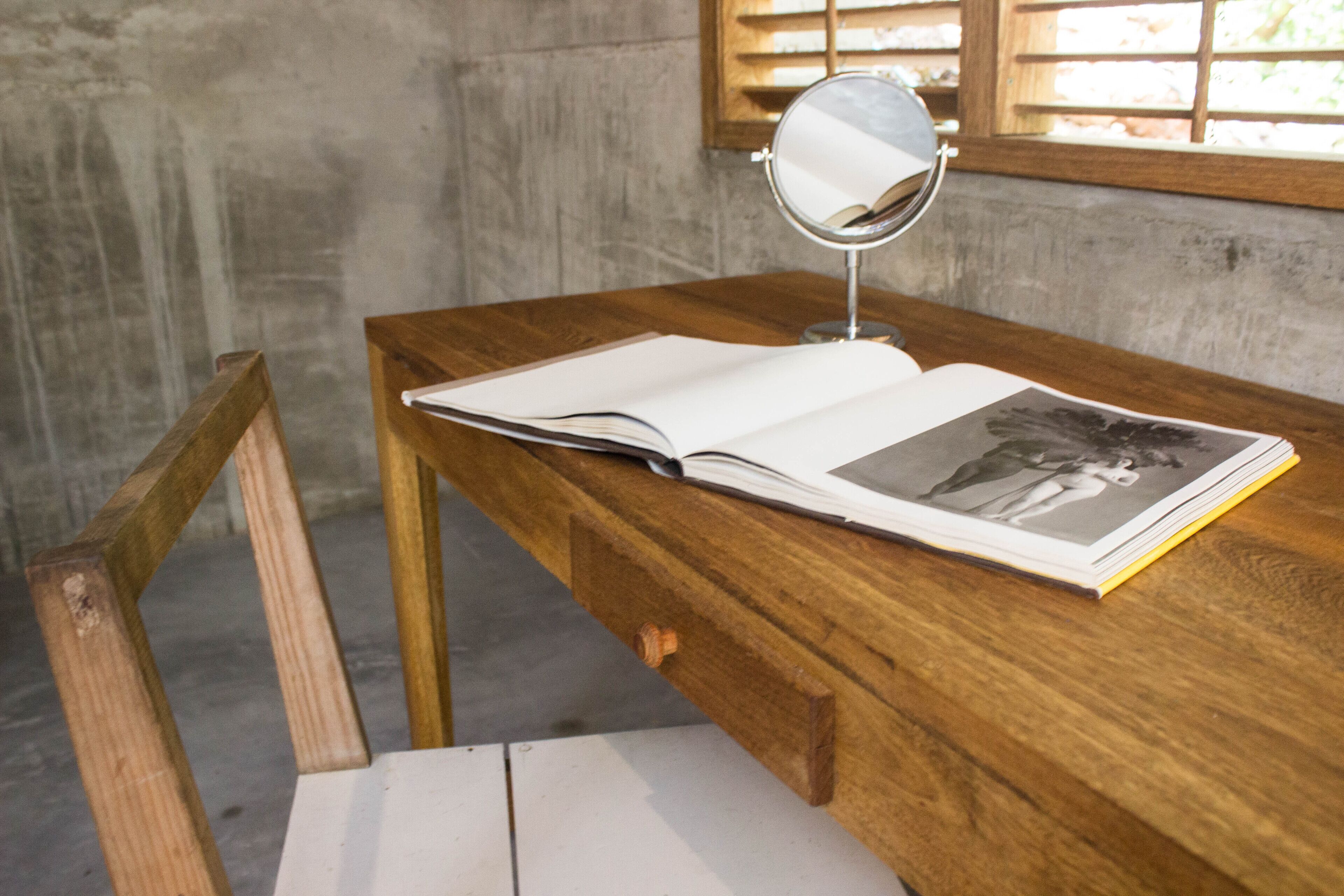 Un escritorio de madera con un libro y un espejo.