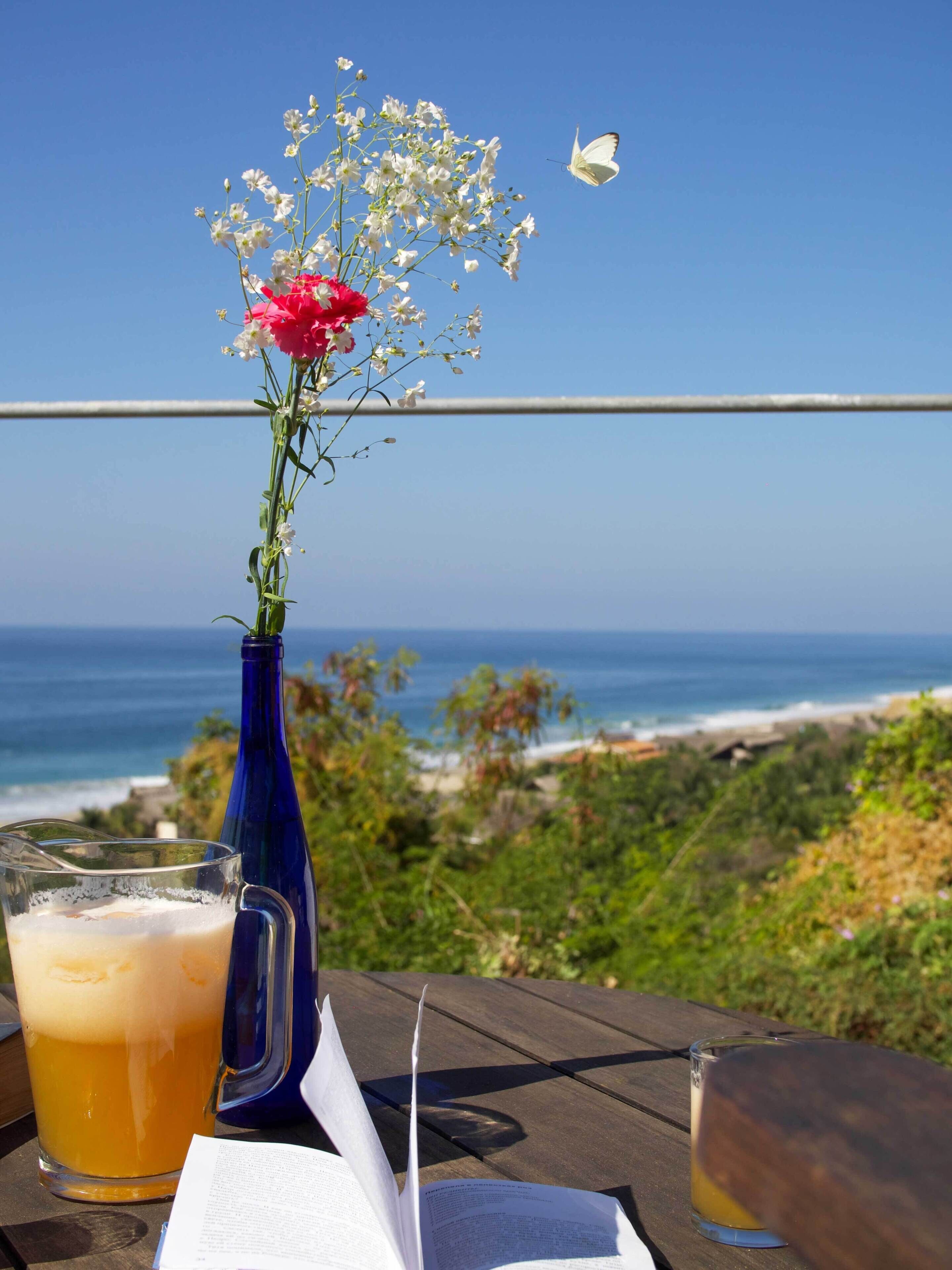 Una mesa con una jarra de cerveza, un libro y un florero con flores.