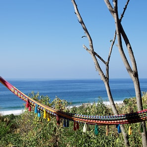 A hammock tied between trees overlooking the ocean.