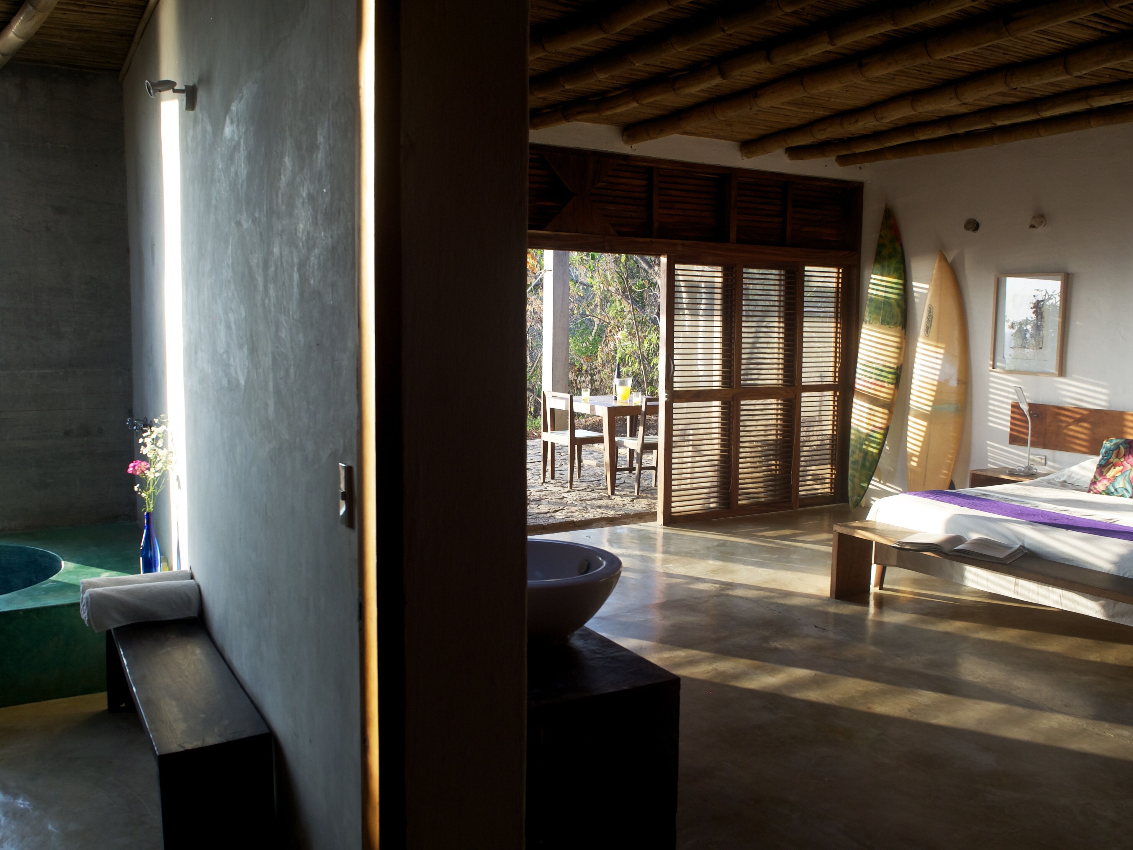 Una habitación con una cama, un ventanal grande, techo de madera y vistas al exterior.