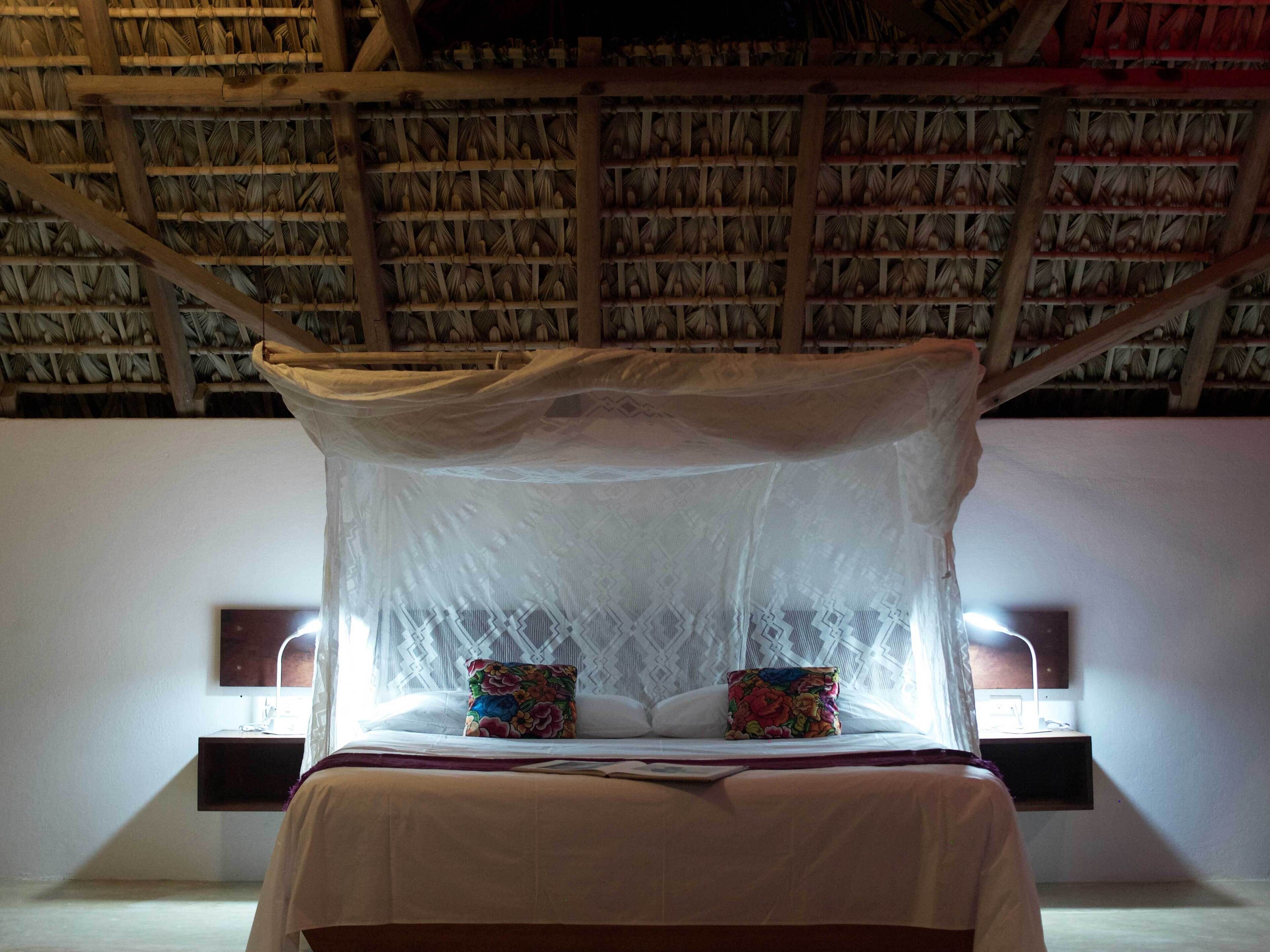 A bed with a canopy, two pillows, bedside lamps, and a nightstand.