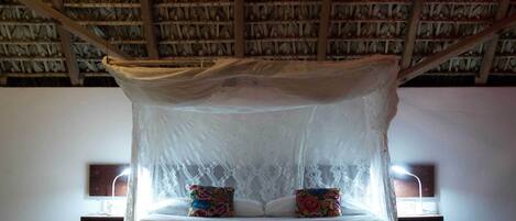 A bed with a canopy, two pillows, bedside lamps, and a nightstand.
