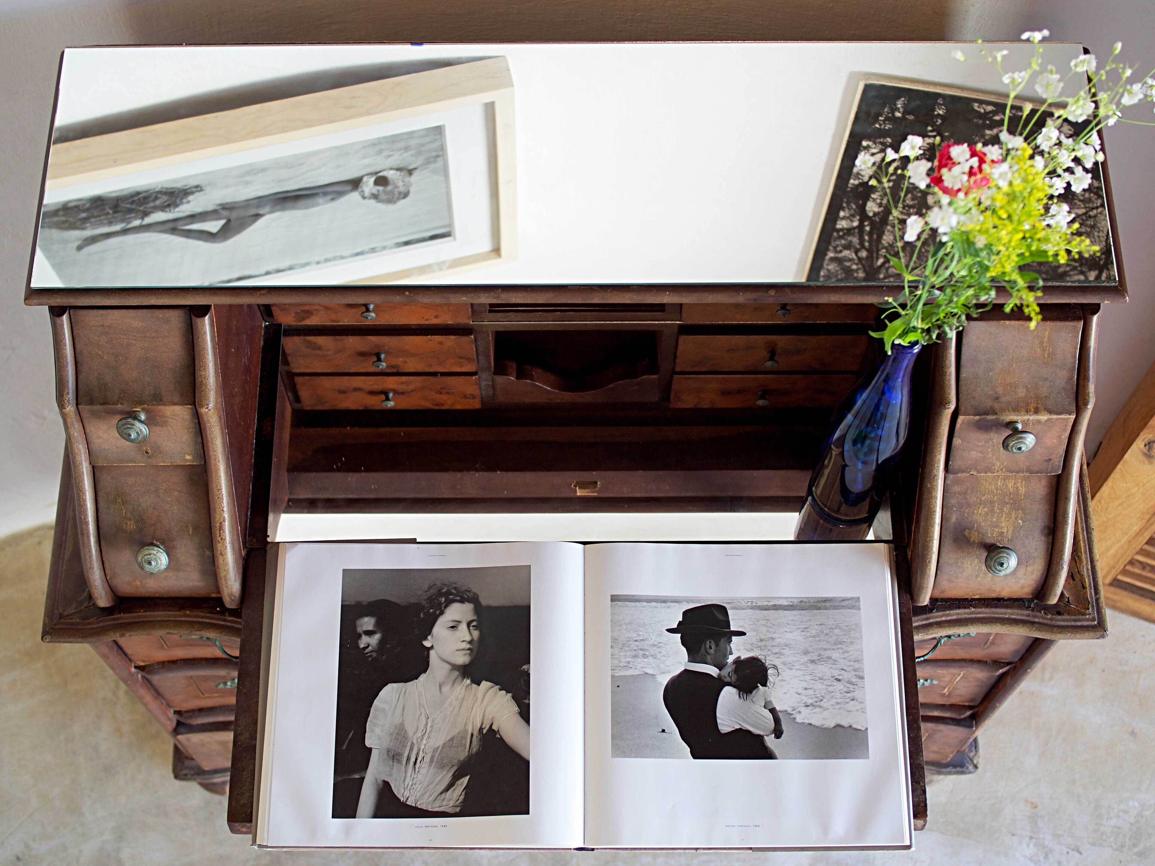A vintage wooden chest with a mirror, drawers, and a vase with flowers.