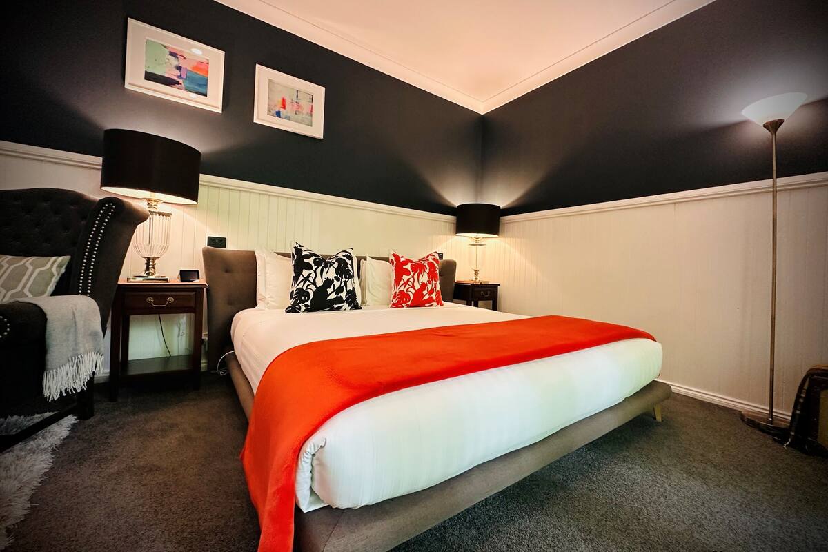 A bedroom with a bed, nightstands, a chair, and a lamp.
