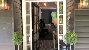 Entrada de hotel con un felpudo de diseño blanco y negro, un arco acogedor y dos plantas en macetas a cada lado.