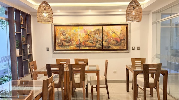 A dining area with wooden furniture and a large painting on the wall. - Rivera del Rio Hotel (Piura)