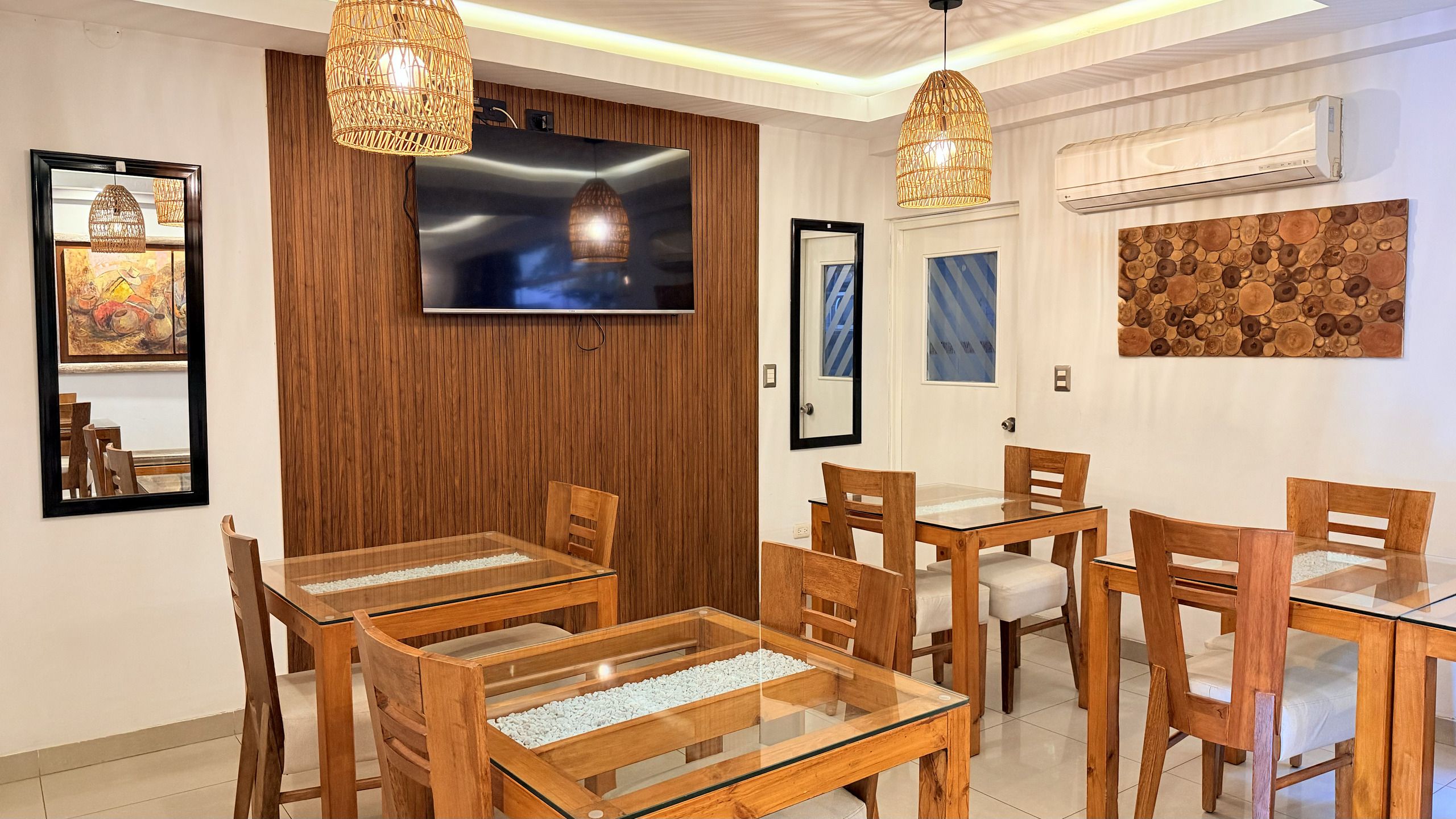 Un comedor con mobiliario de madera y un televisor montado en la pared.