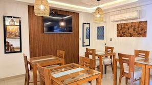 A dining area with wooden furniture and a television mounted on the wall. - Rivera del Rio Hotel (Piura)