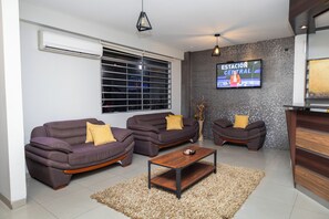 Una sala de estar con dos sofás, una mesa de centro y un televisor montado en la pared.