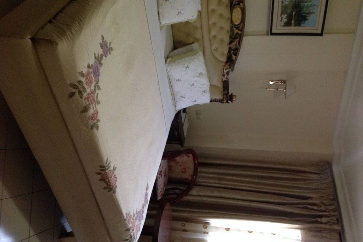 A bedroom with a bed, a nightstand, a mirror, and a framed picture on the wall.