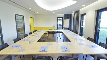 A conference room with a long table, chairs, and a projector screen.