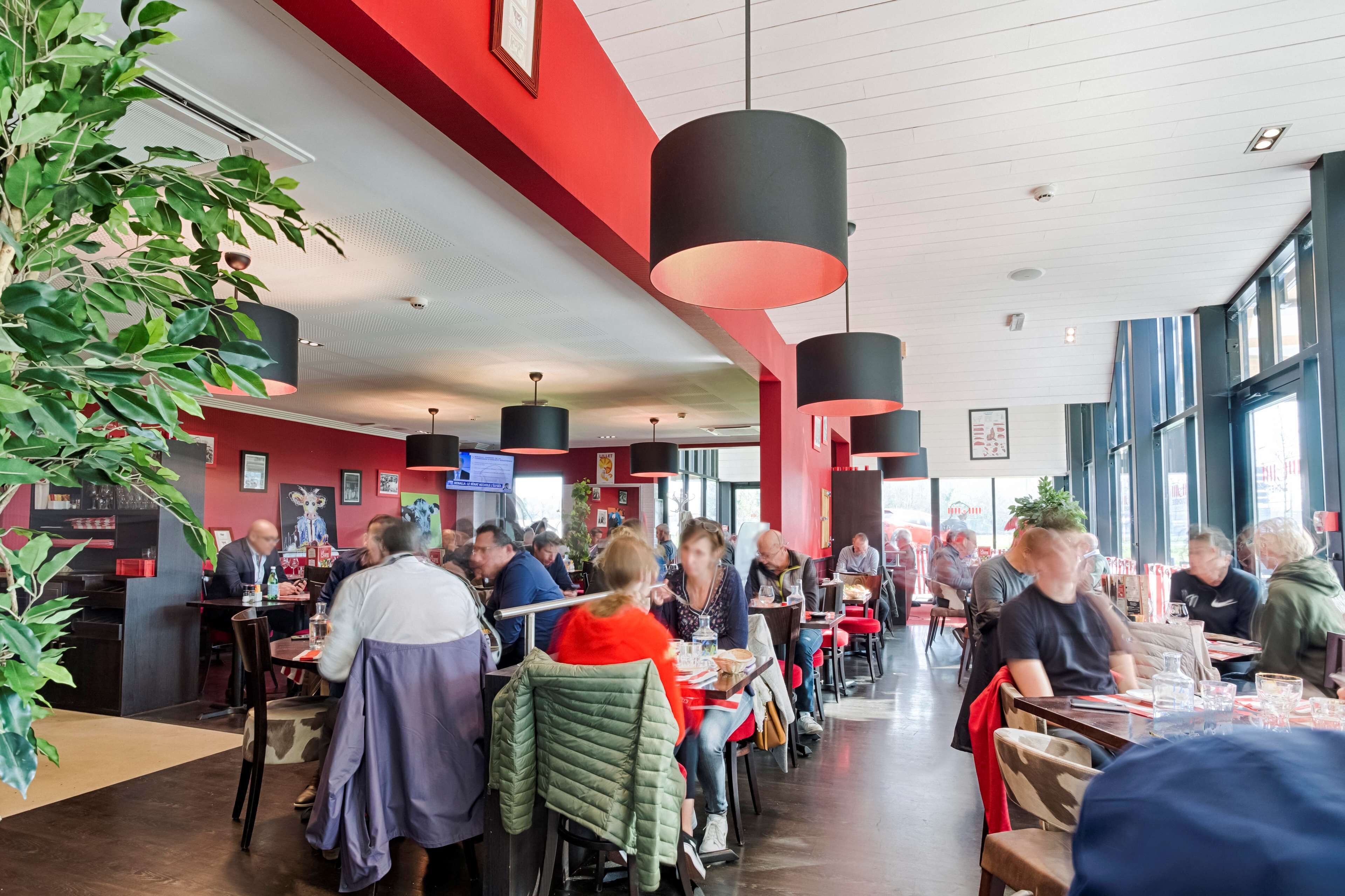 Een restaurant met rode wanden, zwarte hanglampen en grote ramen.