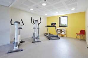 Een fitnessruimte met loopbanden, elliptische trainers en een rode stoel.