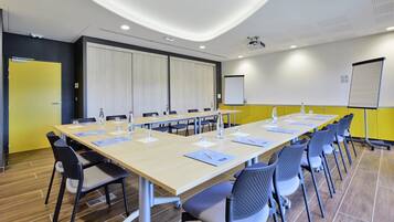 A conference room with a long table, chairs, a projector, and a whiteboard.