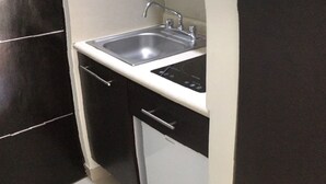 A compact kitchen with a sink, microwave, and cabinets.