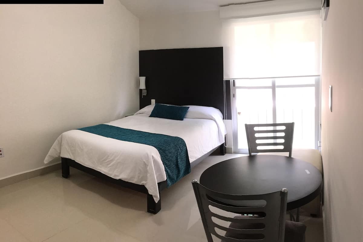 A neatly arranged hotel room with a bed, a small table, and a chair.