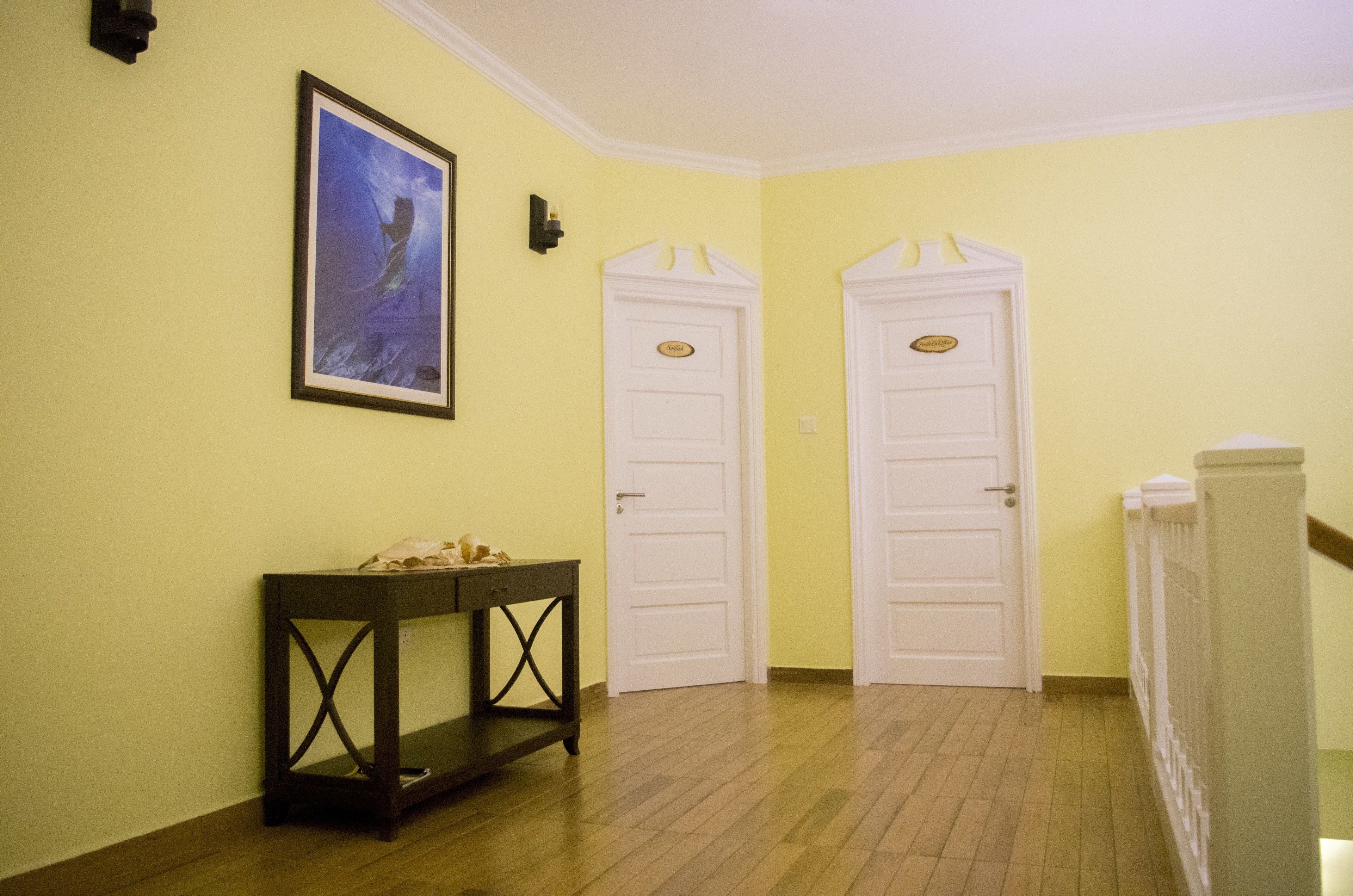 Un pasillo con dos puertas blancas, un cuadro en la pared y una consola de madera oscura.