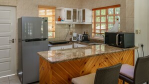 Cocina equipada con refrigerador, microondas, cafetera y armarios de madera.