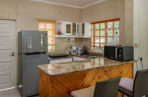 Cocina equipada con refrigerador, microondas, cafetera y armarios de madera.