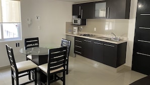 A compact kitchen with a dining table and chairs, a microwave, a stove, and a sink. - Grupo Kings Suites Chimborazo (Mexico City)