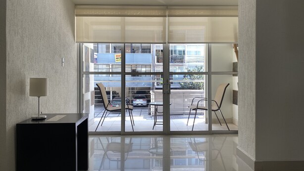 A modern interior with a glass door leading to an outdoor balcony with chairs and a table. - Grupo Kings Suites Chimborazo (Mexico City)
