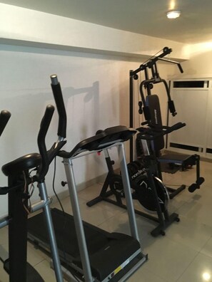A home gym with a treadmill, elliptical, and weight machine.