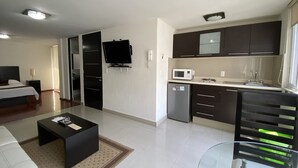 A modern hotel room with a bed, a TV, a kitchenette, and a glass table. - Grupo Kings Suites Chimborazo (Mexico City)