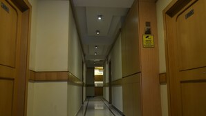Un pasillo con puertas de madera, un letrero de circuito cerrado de televisión y piso de baldosas.