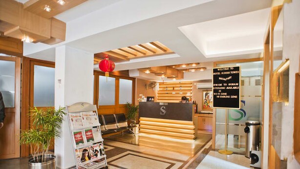 Zona de recepción de hotel con mostrador, área de asientos y señal de disponibilidad de Wi-Fi.