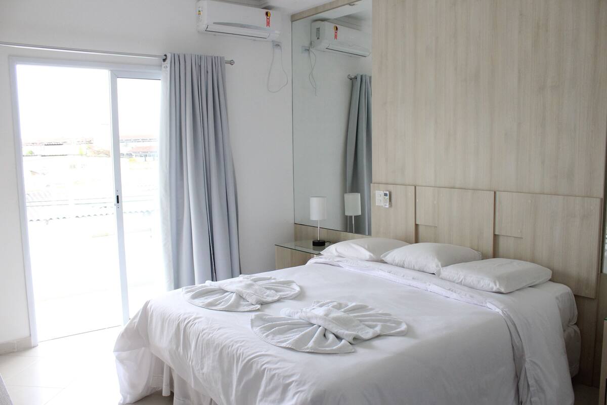A hotel room with a bed, a bathroom, and a balcony.