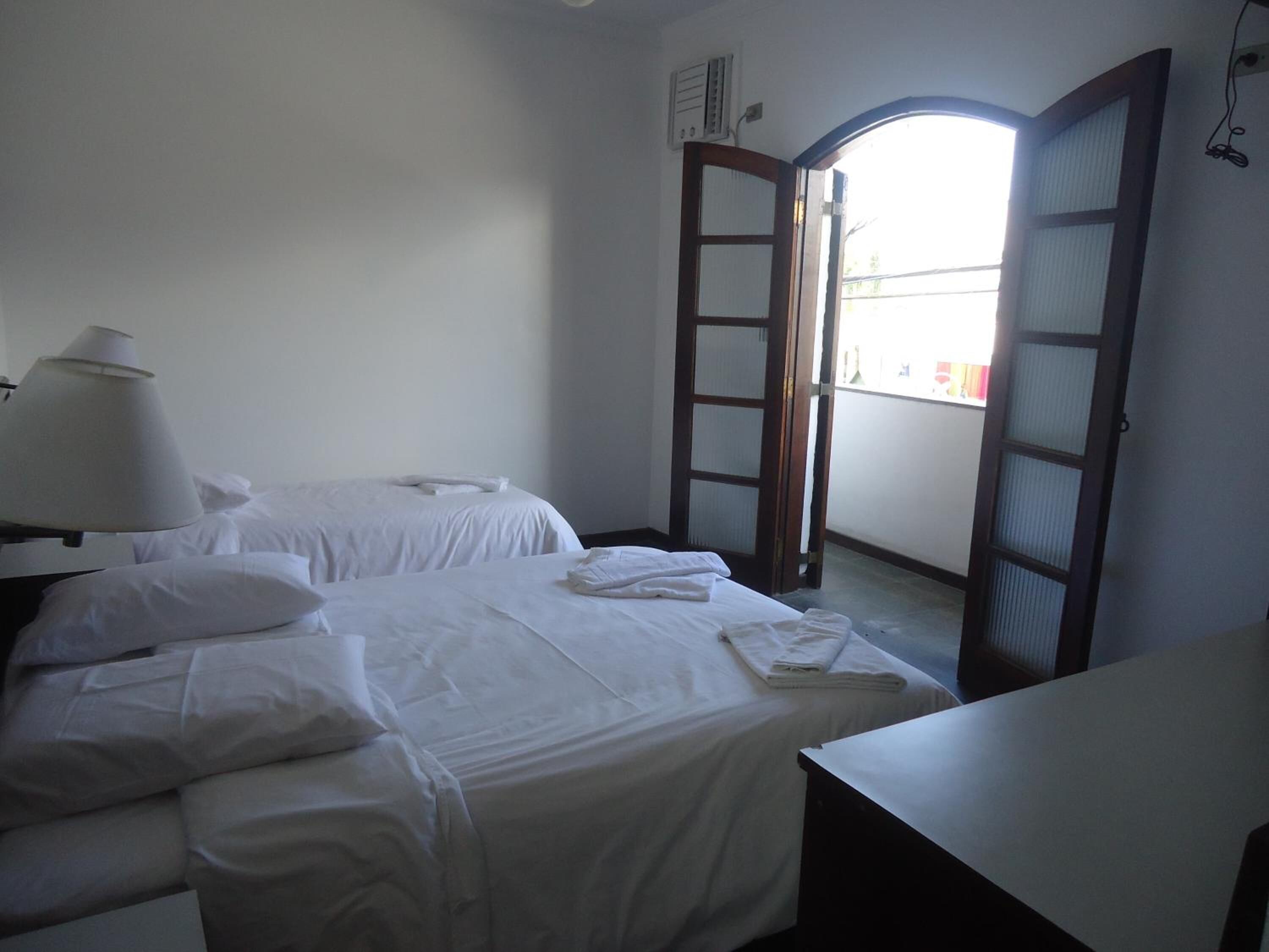 A hotel room with two beds, a desk, and a window with a view of the outside.