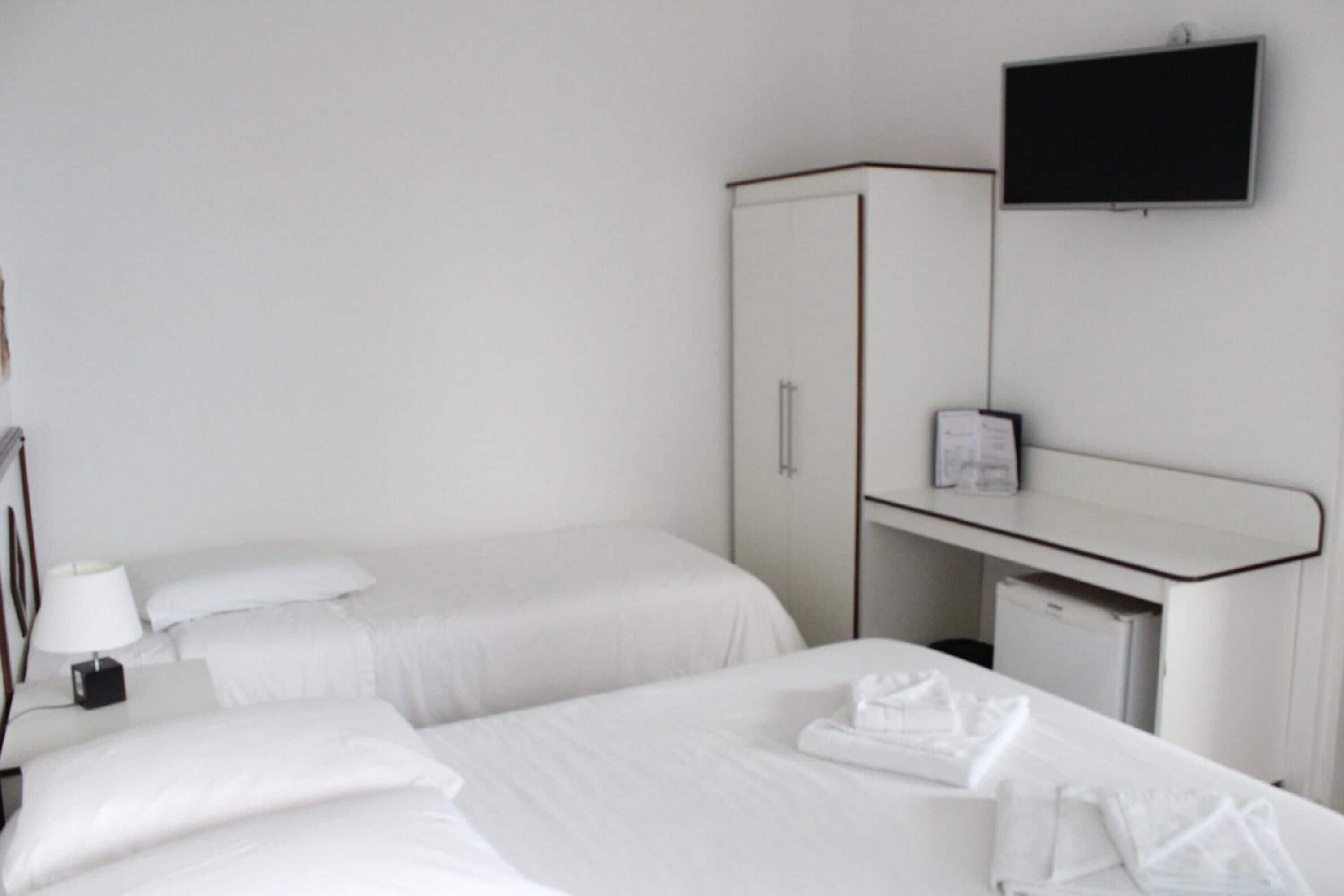 A hotel room with two beds, a desk, a television, and a wardrobe.