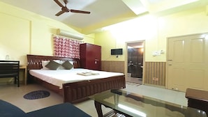 A bedroom with a bed, a desk, a chair, a wardrobe, a TV, and a bathroom door. - Hotel Avisha (Barasat)