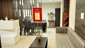 A reception area with a 'Welcome to Hotel Avisha' sign, a reception desk, a sofa, and a decorative plant on a table. - Hotel Avisha (Barasat)