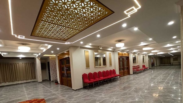 A spacious hall with a polished marble floor, rows of red chairs, and a decorative ceiling panel. - Hotel Avisha (Barasat)