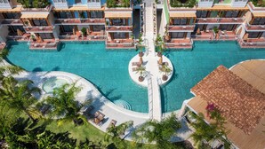 Un complejo turístico con varias edificaciones, una piscina central y palmeras circundantes.