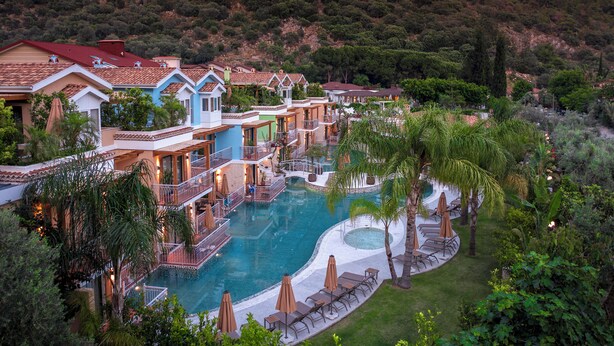 Un resort con una piscina grande, varias construcciones y abundante vegetación.