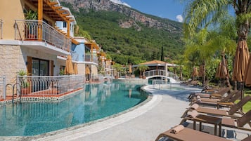Un complexe hôtelier doté d’une piscine, de chaises longues et offrant une vue sur les montagnes.