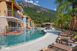 Un complexe hôtelier doté d’une piscine, de chaises longues et offrant une vue sur les montagnes.