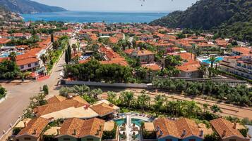Uma cidade costeira com edifícios de telhado vermelho, uma piscina central e vista para o mar.