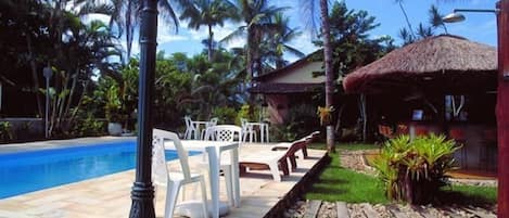 Una piscina al aire libre, sombrillas, sillones reclinables de piscina