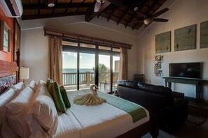 Una habitación de hotel con cama, sofá, televisión y balcón con vista al océano.