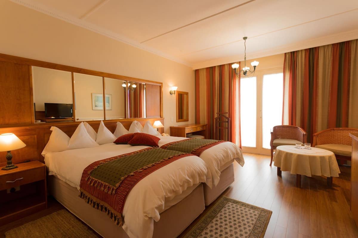 Une chambre d’hôtel avec un grand lit, un bureau, une chaise, une petite table et un téléviseur.