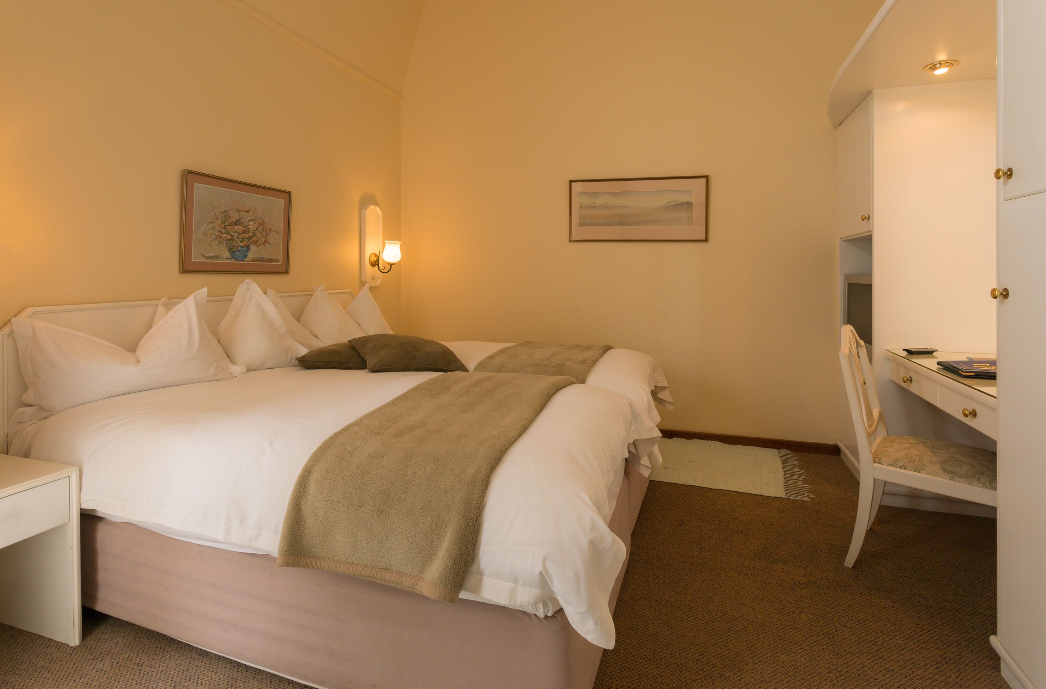 Une chambre bien rangée, avec un lit, une table de chevet et un bureau avec une chaise.