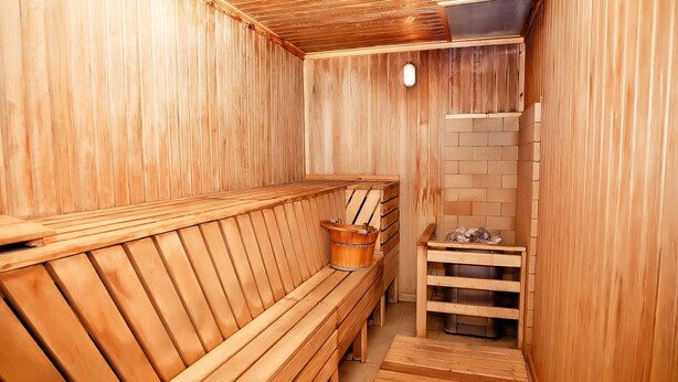 A wooden sauna with benches and a wooden bench. - City Hotel Tien Shan (Almaty)