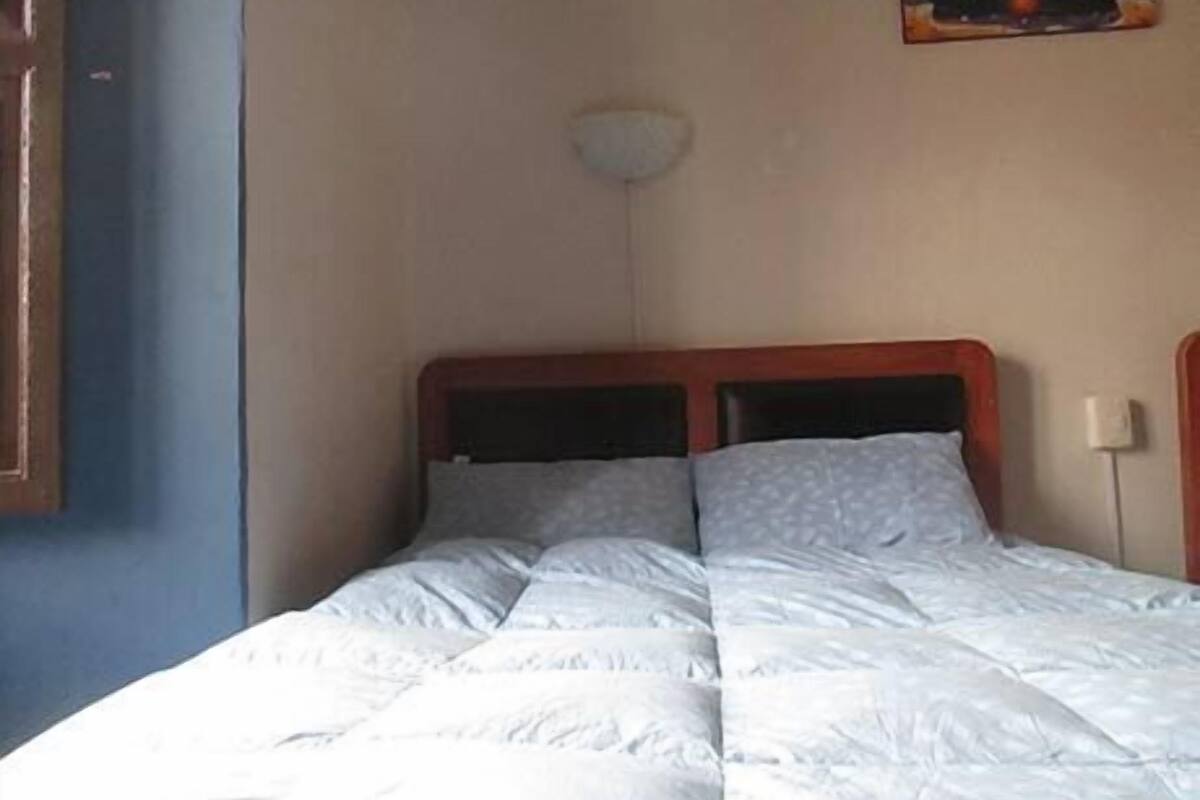 A single bed with a wooden headboard, a white duvet, and two pillows.