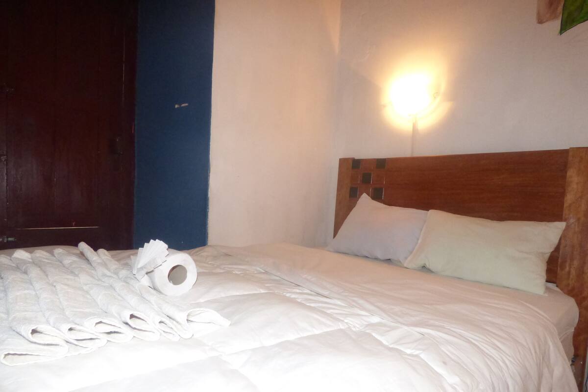 A neatly made bed with white linens and a rolled-up towel.