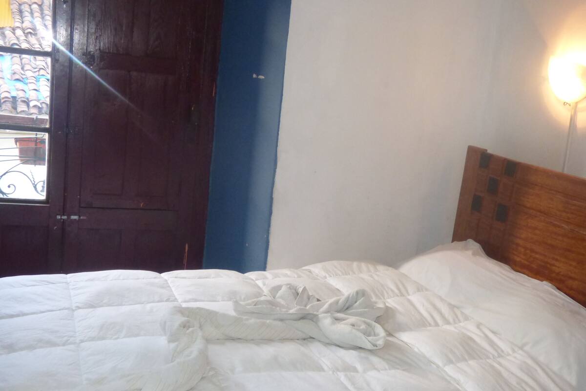 A bed with white bedding, a wooden headboard, and a blue wall.