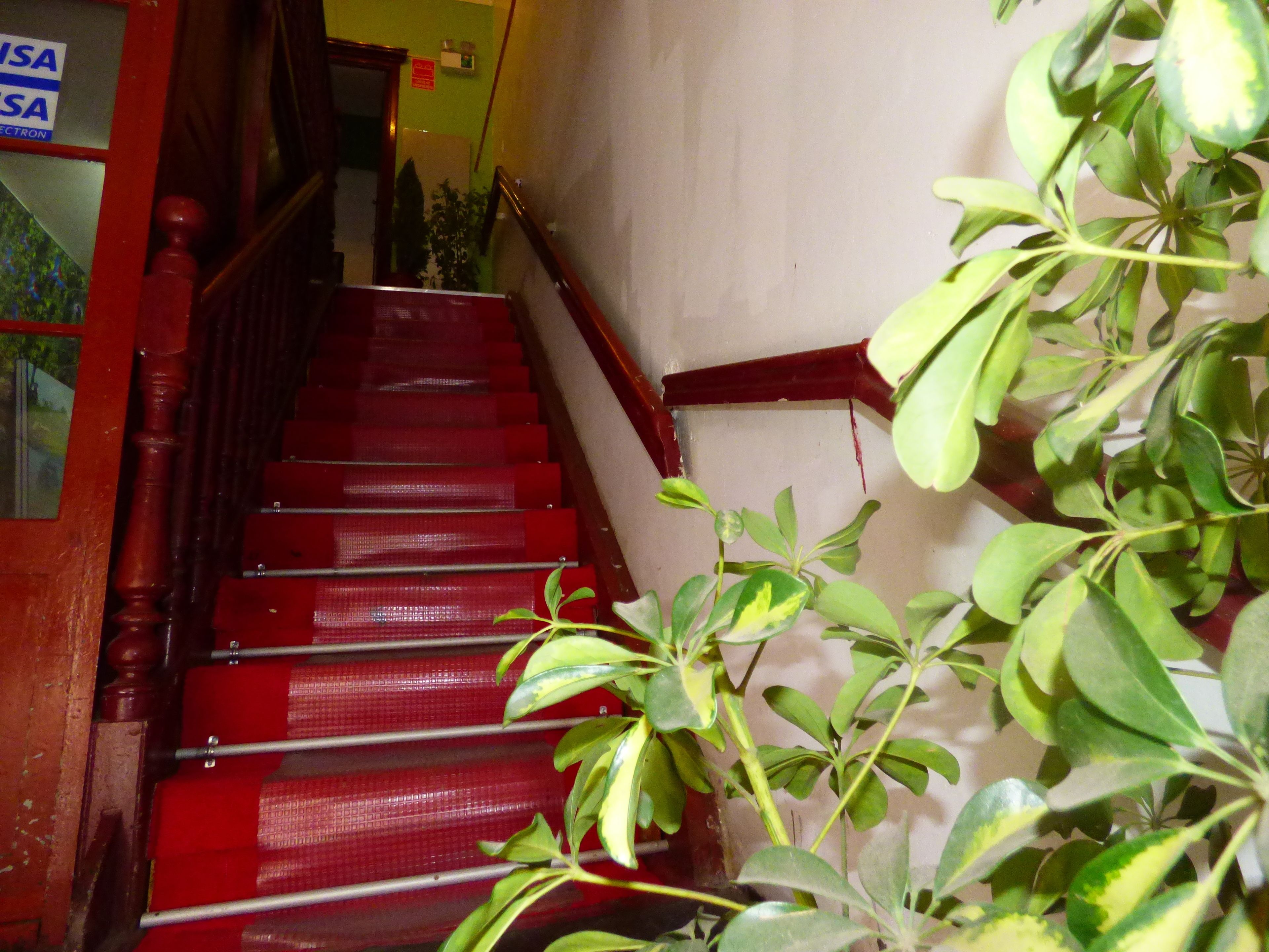 Una escalera con escalones rojos y barandal de madera.